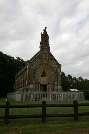 Une église historique dotée d’un haut clocher, entourée d’une clôture en métal et, au premier plan, d’une clôture en bois.