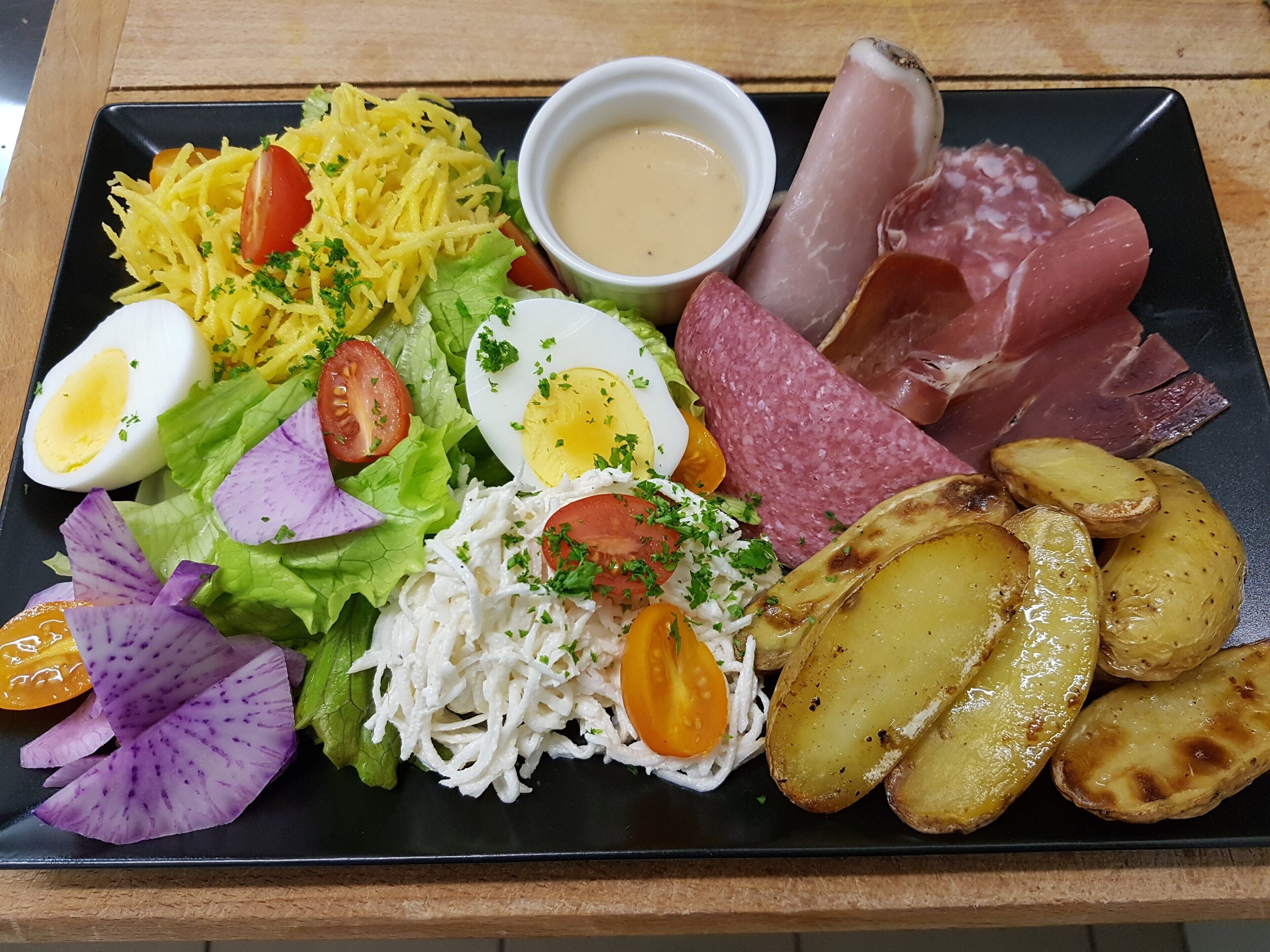 A plate with a variety of foods including potatoes, eggs, and meats.