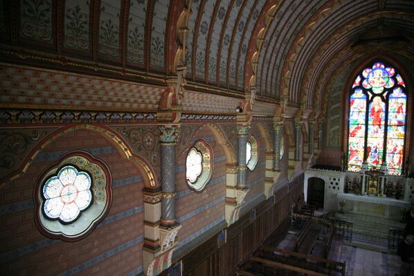 An interior with arched ceilings, stained glass windows, and brick walls.