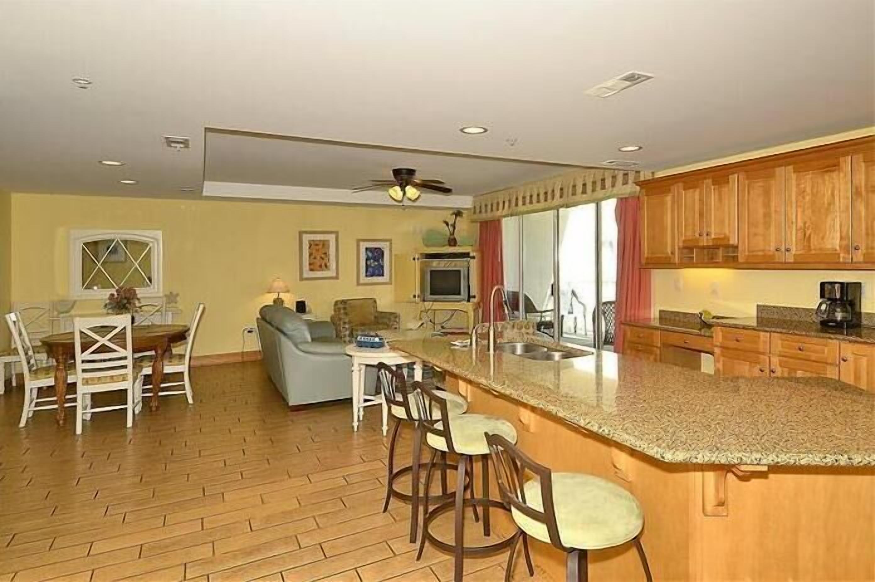 A spacious kitchen with wooden cabinets, a granite countertop, and a dining area with a table and chairs.