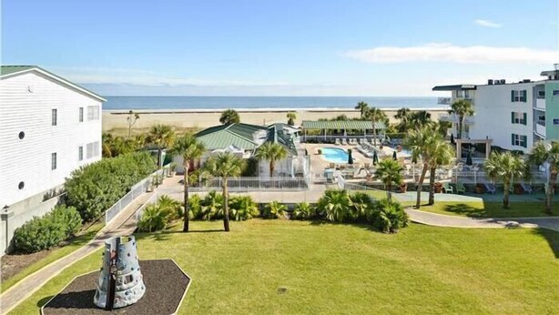 Un complexe hôtelier doté d’une piscine, de palmiers et offrant une vue sur la plage.