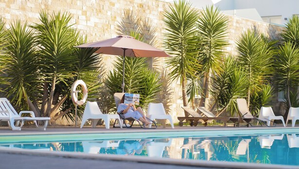 Ein Poolbereich mit Liegestühlen, einem Pool und Palmen.