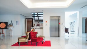 Eine moderne Lobby mit rotem Teppich, einem Empfangsschalter und einer Treppe.