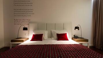 Habitació d'hotel amb un llit gran, dues taules de nit i una paret amb un poema.