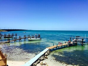 Un muelle que se adentra en aguas azules y transparentes, con barcos amarrados.