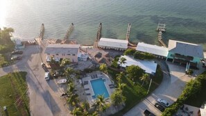 Eine Vogelperspektive eines Küstenhotels mit Pool, mehreren Gebäuden und einer Pier, die ins Wasser ragt.