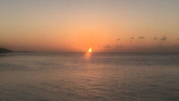 A sunset over a calm sea with a distant shoreline.