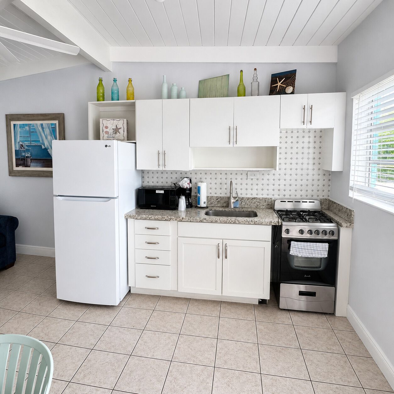 A modern kitchen with white cabinetry, a built-in microwave, a gas stove, and a refrigerator.