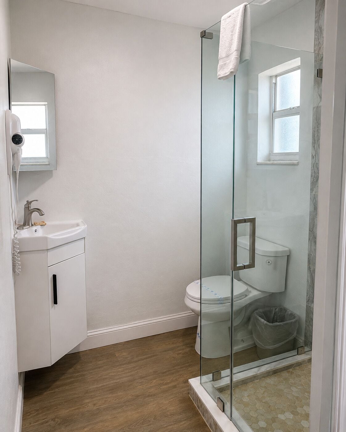 A bathroom with a glass-enclosed shower, a white sink, and a toilet.
