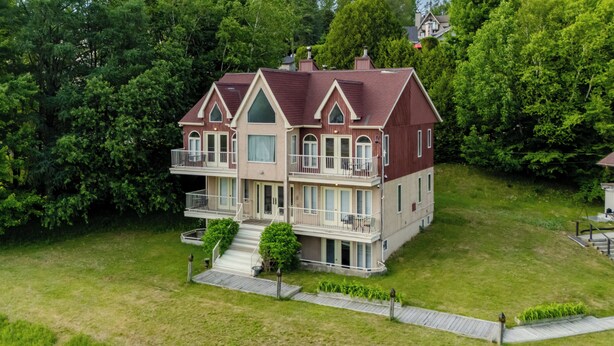 Une maison à deux étages dotée d’un balcon, entourée de verdure.
