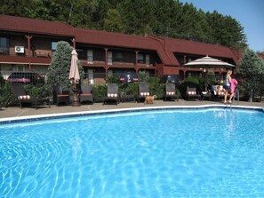 Una piscina al aire libre, sombrillas, sillones reclinables de piscina