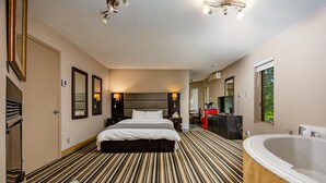 Une chambre d’hôtel avec un grand lit, une salle de bain séparée avec une baignoire et une vue sur l’extérieur.