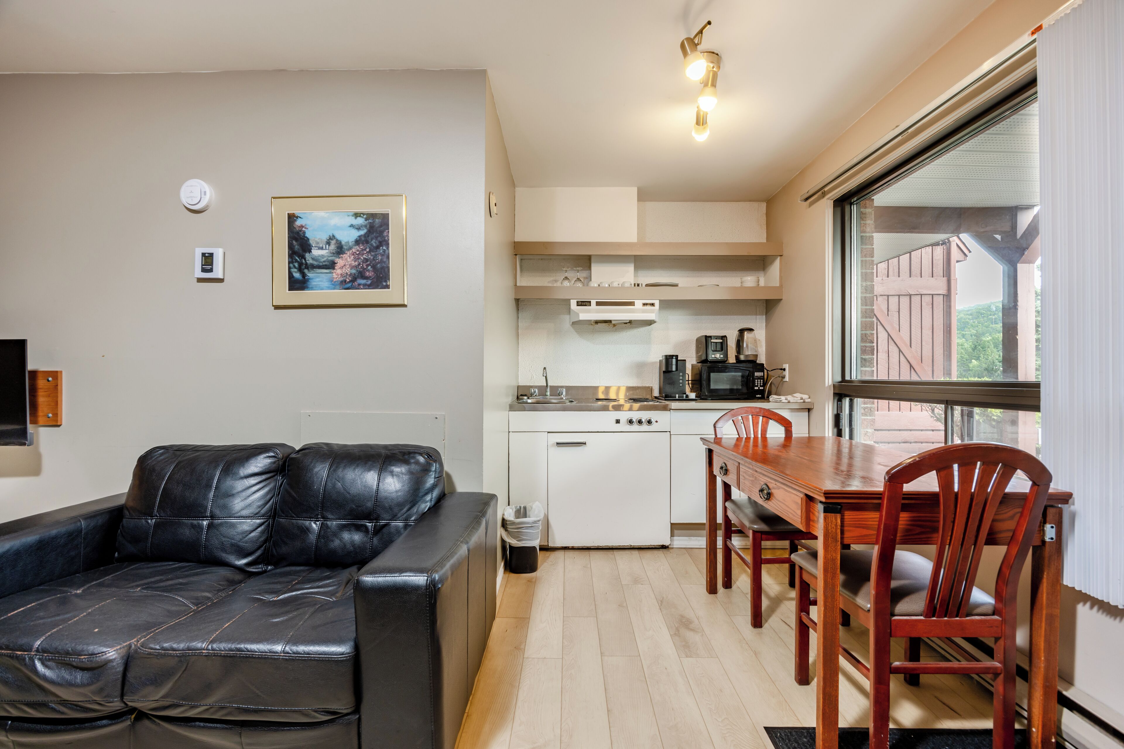 Un espacio habitable compacto con kitchenette, comedor y zona de estar con sofá.