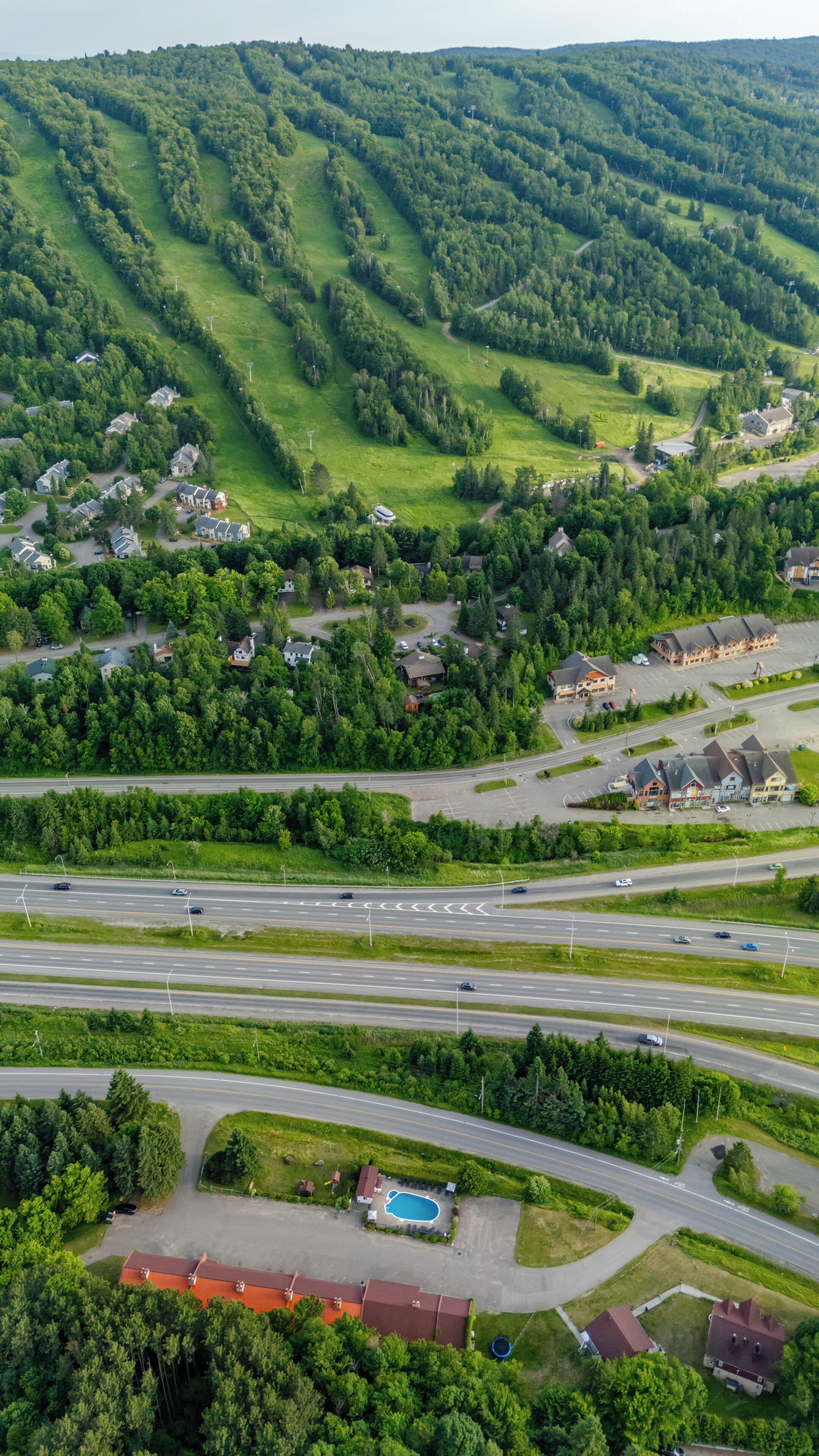 An aerial view of a residential area with houses, roads, and a swimming pool.