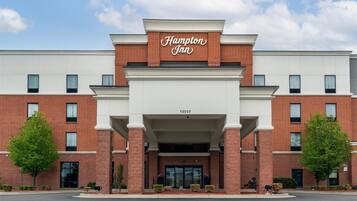 A Hampton Inn with a brick facade, large windows, and a clear sky.
