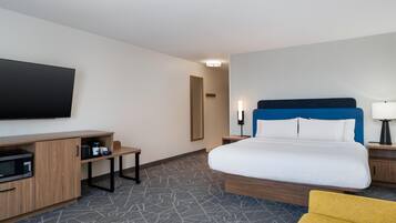 Une chambre d’hôtel avec un lit, une télévision, un bureau et une chaise.