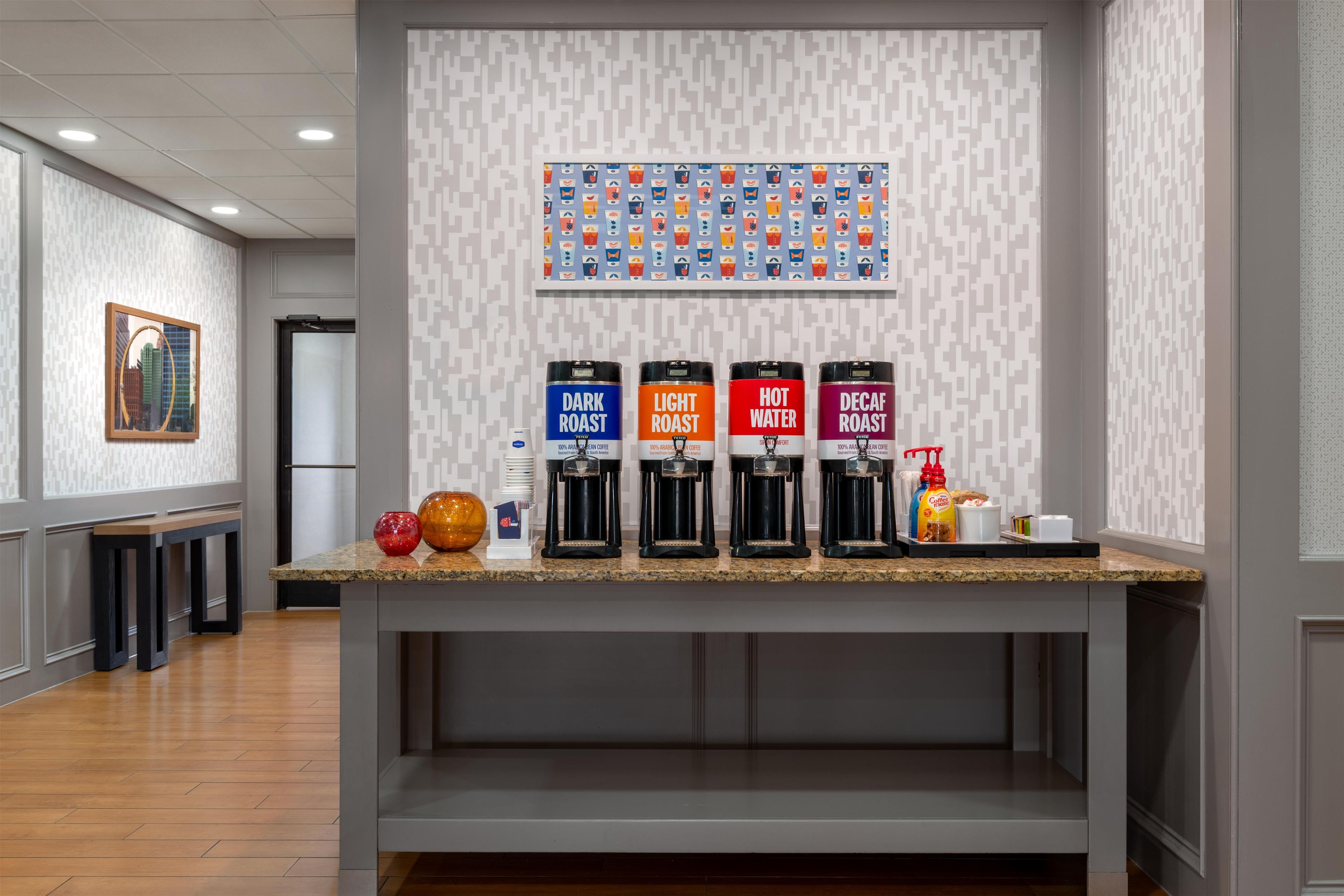 Una estación de café con dispensadores etiquetados para café tostado oscuro, tostado claro, agua caliente y café descafeinado.