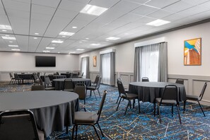 A conference room with round tables, chairs, a flat-screen TV, and a patterned carpet. - Hampton Inn Detroit/Southgate (Southgate)