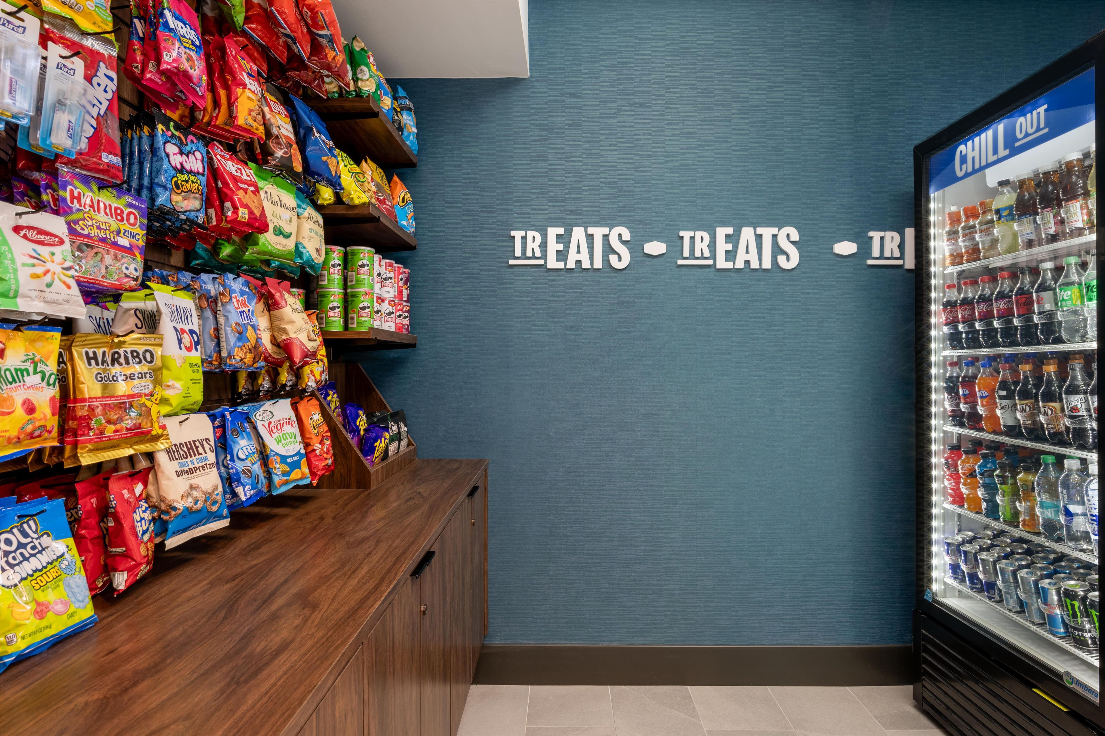 Zona de exhibición de aperitivos y bebidas con diversos productos empaquetados y una sección refrigerada para bebidas.