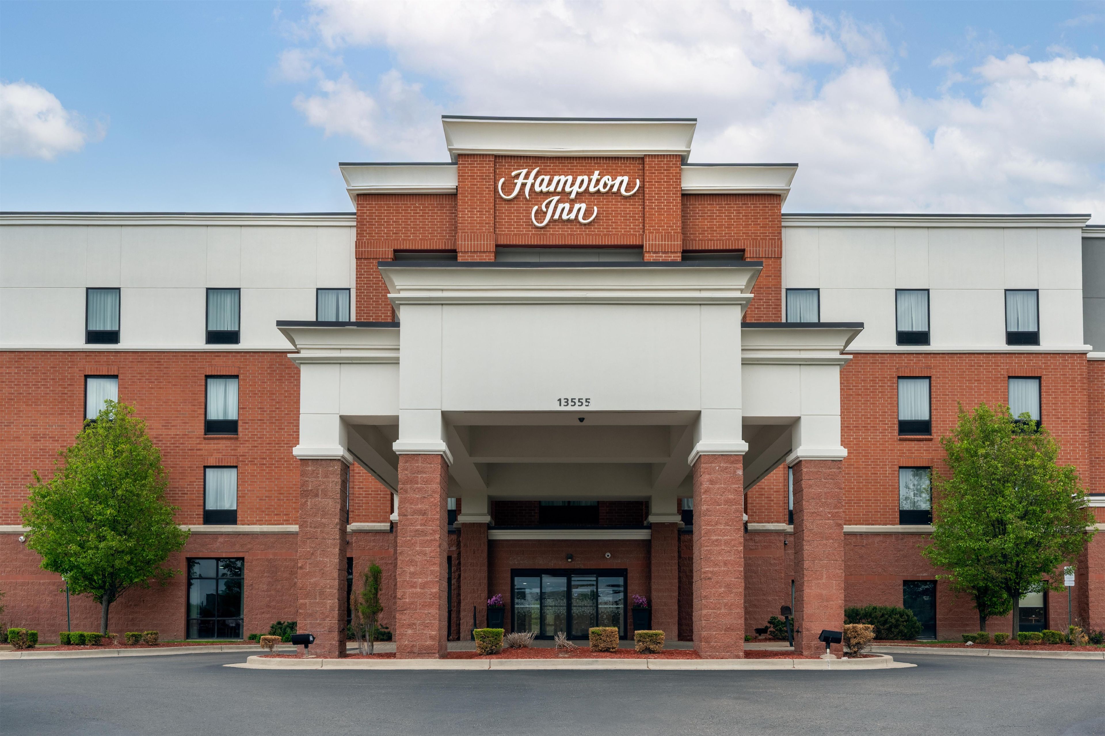 Un hôtel Hampton Inn avec une façade en briques, de grandes fenêtres et un ciel dégagé.