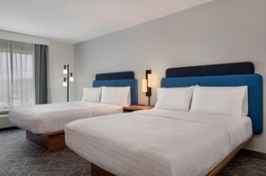 A hotel room with two beds, a nightstand, a lamp, and a large window with curtains. - Hampton Inn Detroit/Southgate (Southgate)