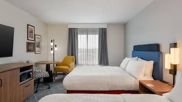 A hotel room with two beds, a desk, a chair, a TV, and a window with curtains.