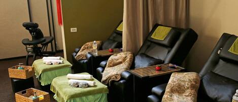 A massage room with multiple massage chairs, green towels, and small woven baskets.