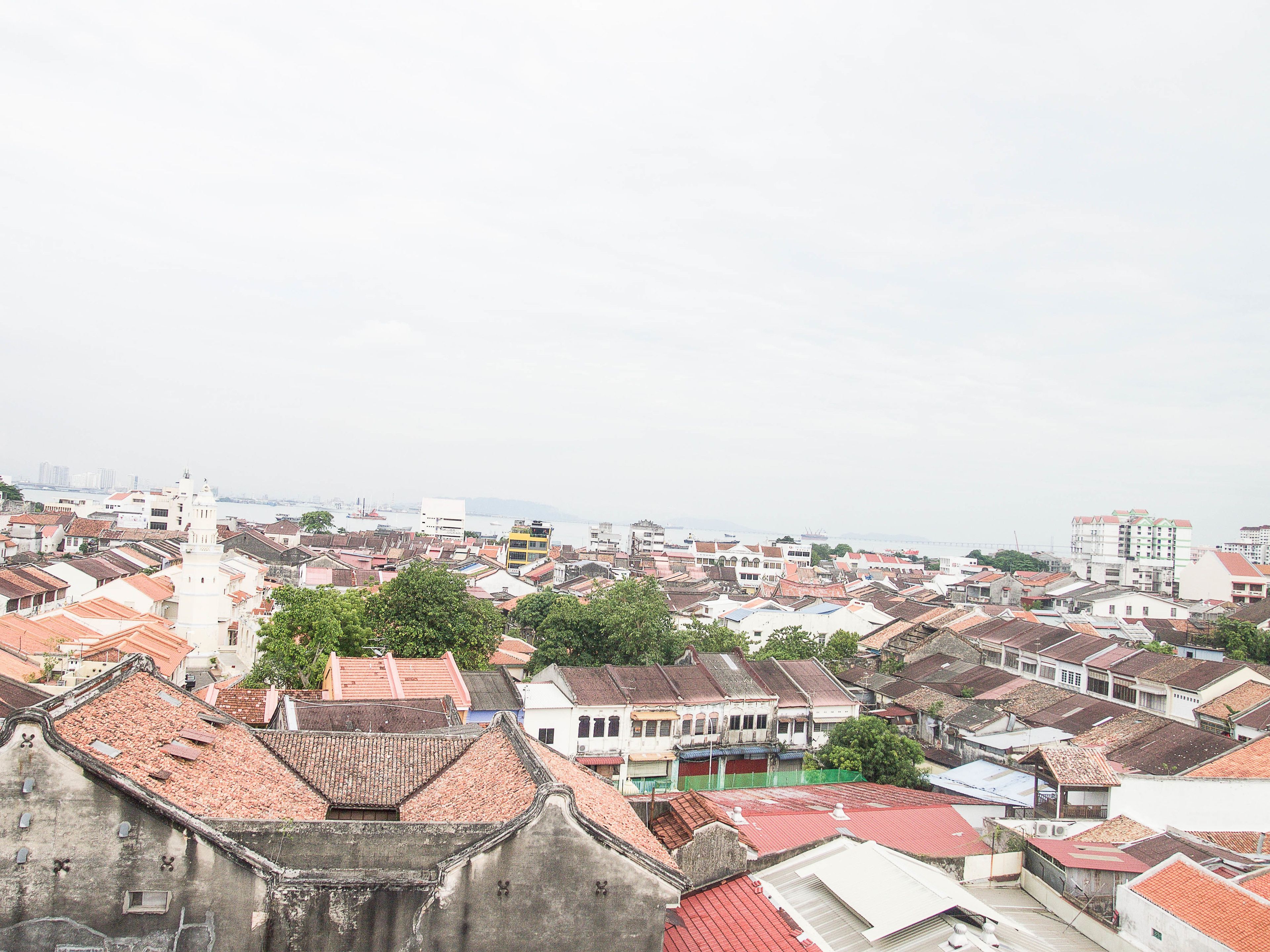 A densely packed urban area with traditional buildings, some with red-tiled roofs, and a prominent white building with a tower.