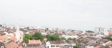 Uma área urbana densa com edifícios tradicionais, alguns com telhados de terracota, e um edifício branco imponente com uma torre.