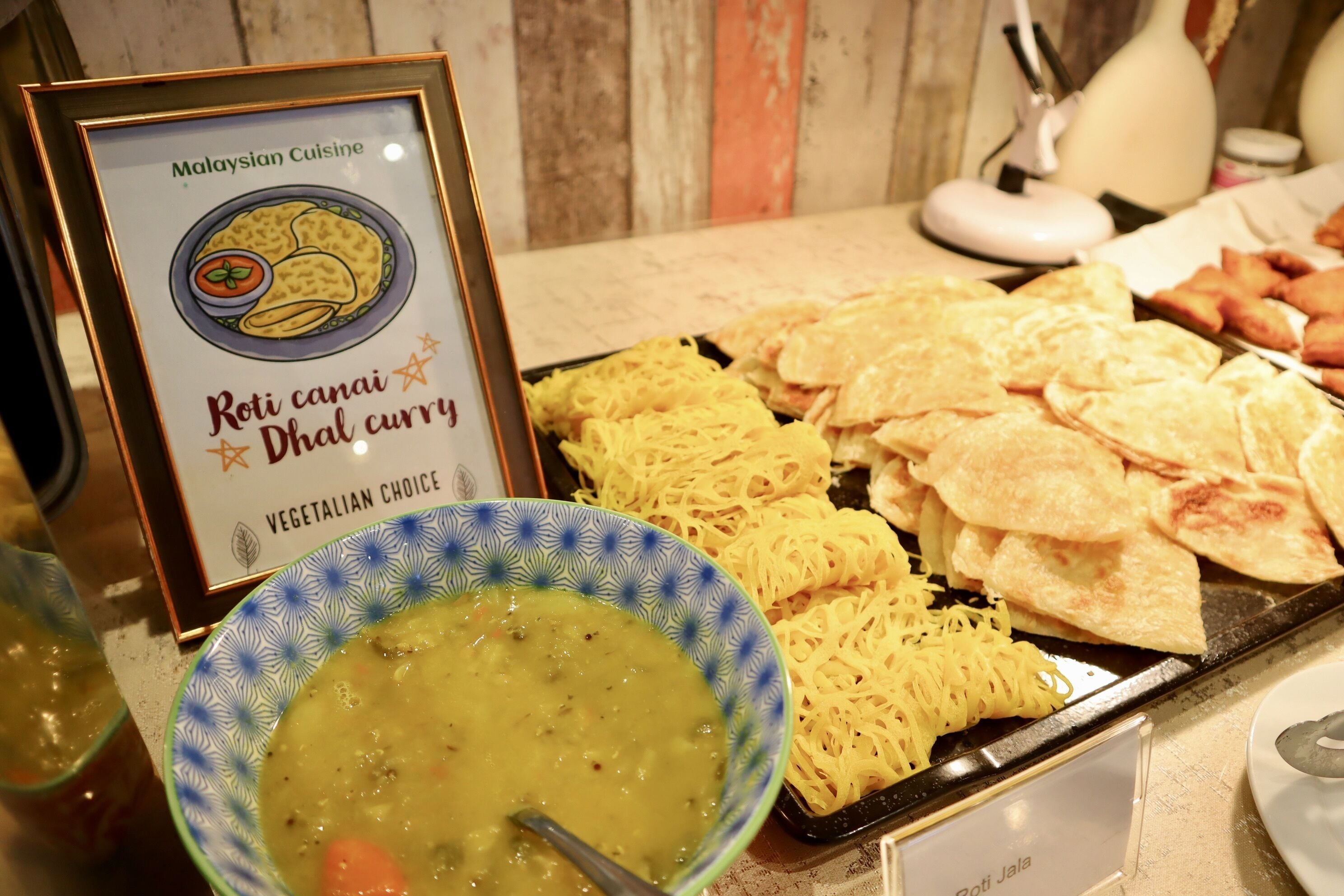 A buffet with Roti canai, dhal curry, and yellow noodles.