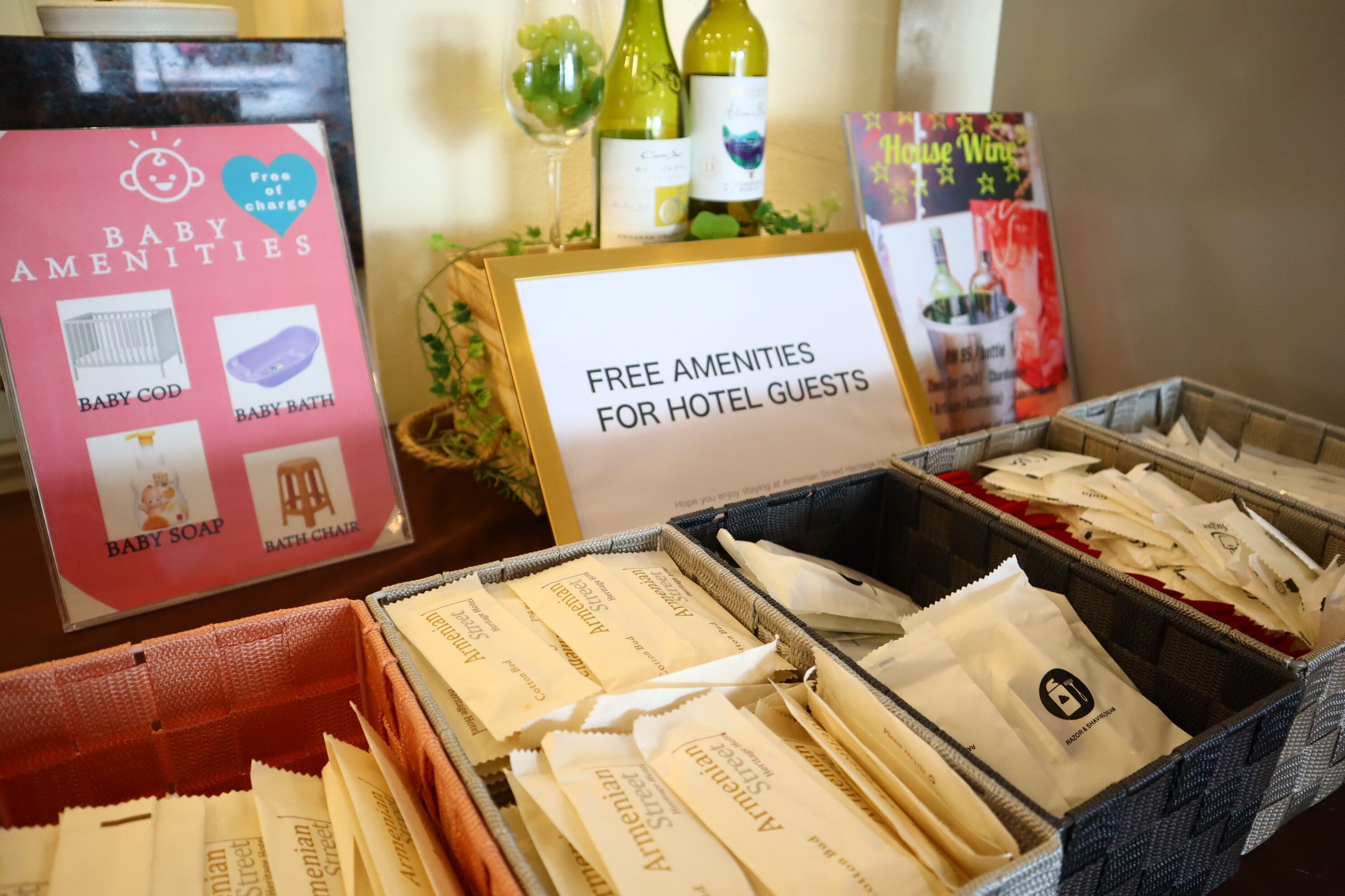 A hotel amenities display with a sign for free amenities for guests, including baby items and toiletries.