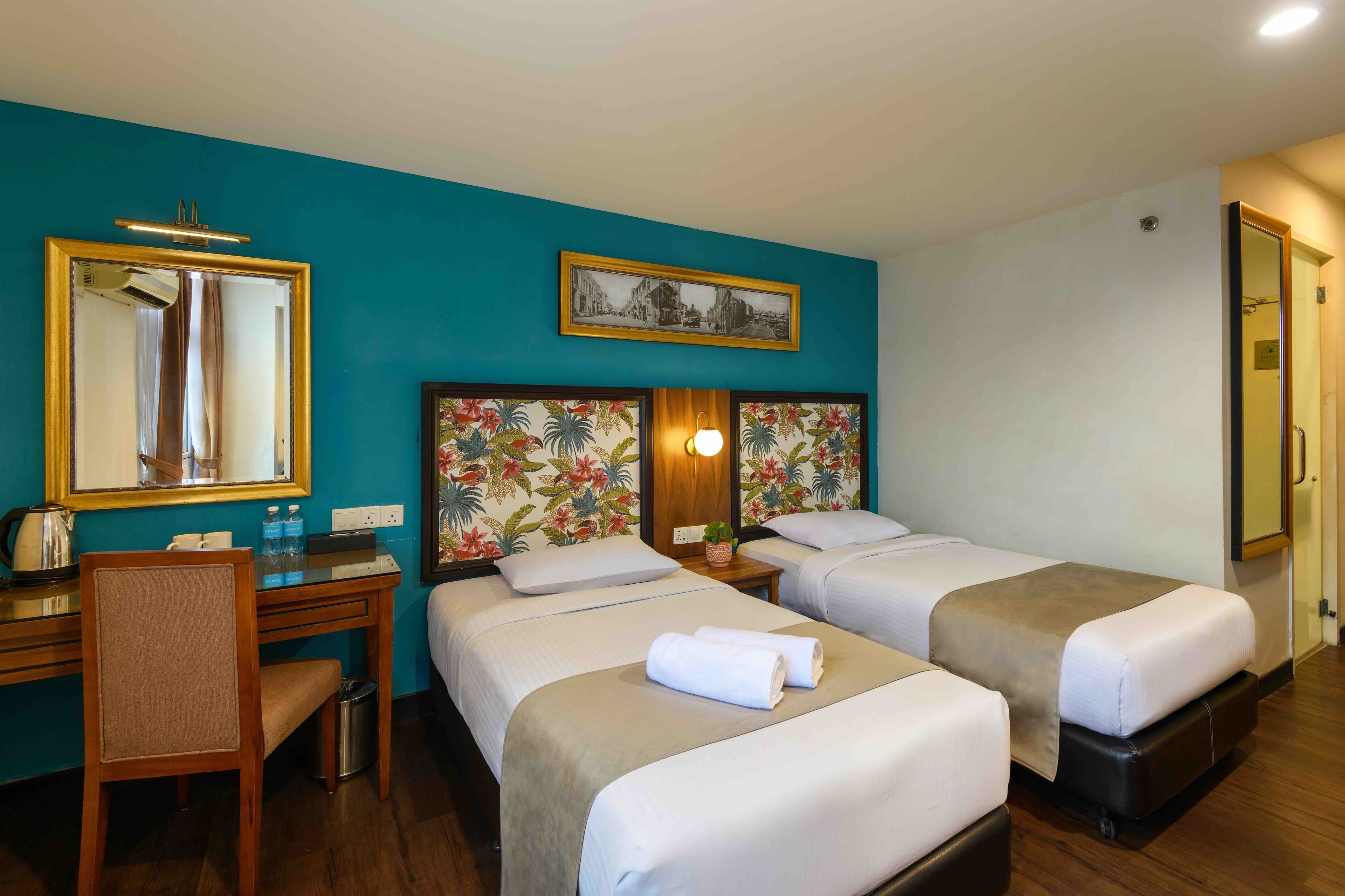 Una habitación de hotel con dos camas, un escritorio, una silla y un espejo.