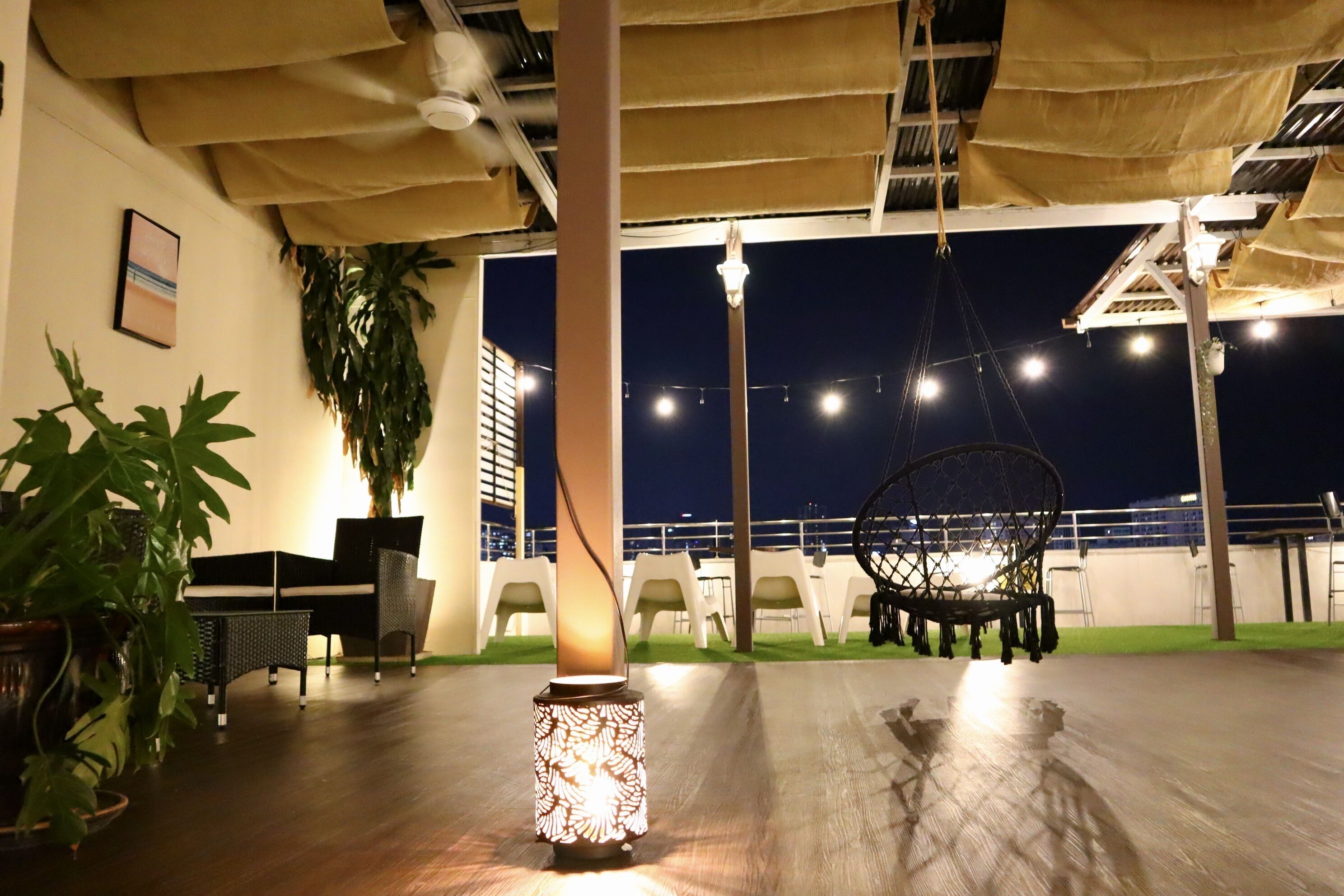An outdoor seating area with tables and chairs, a hanging chair, and a decorative light fixture.