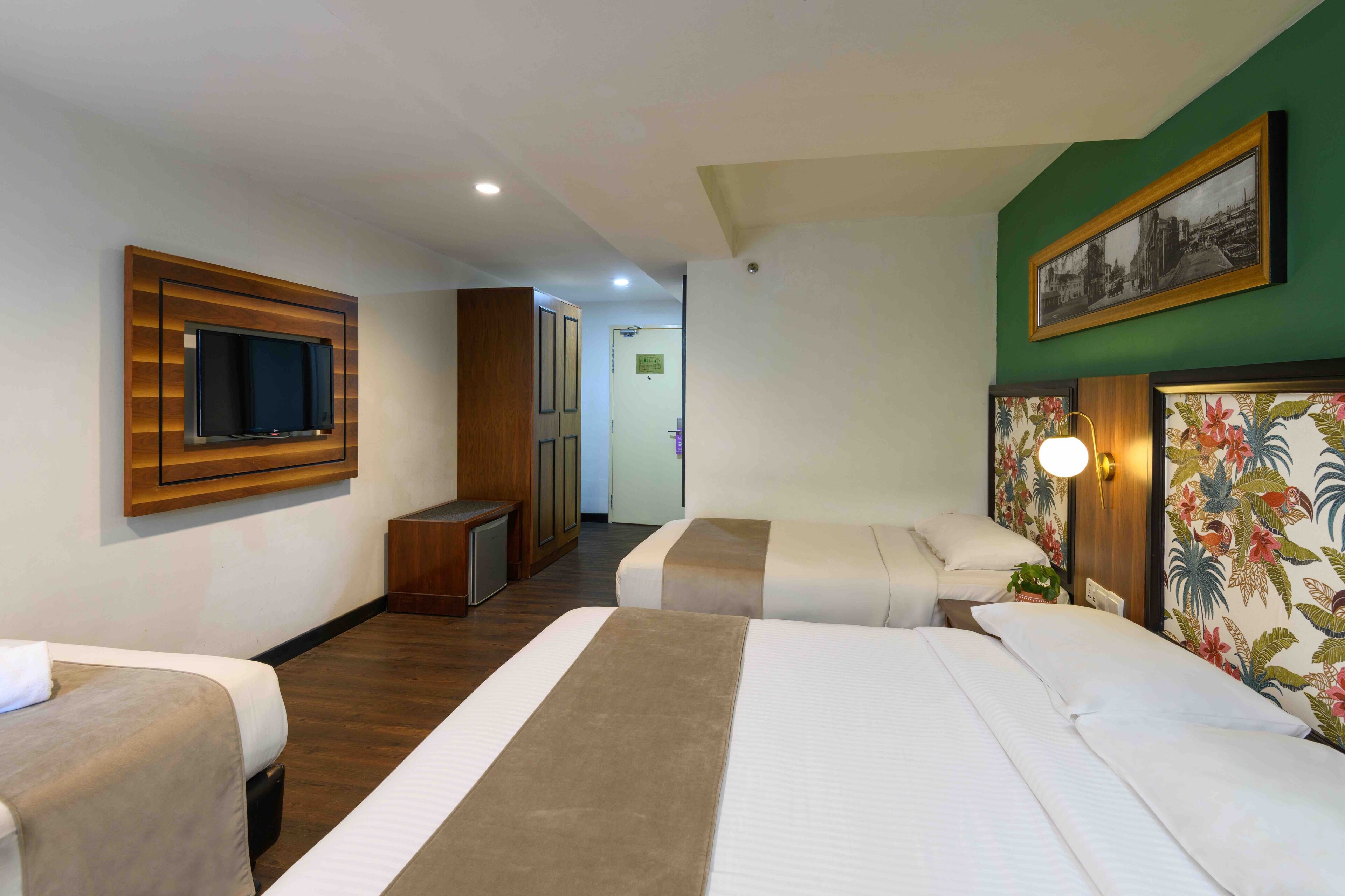 A hotel room with two beds, a TV mounted on the wall, a desk, and a door leading to a bathroom.