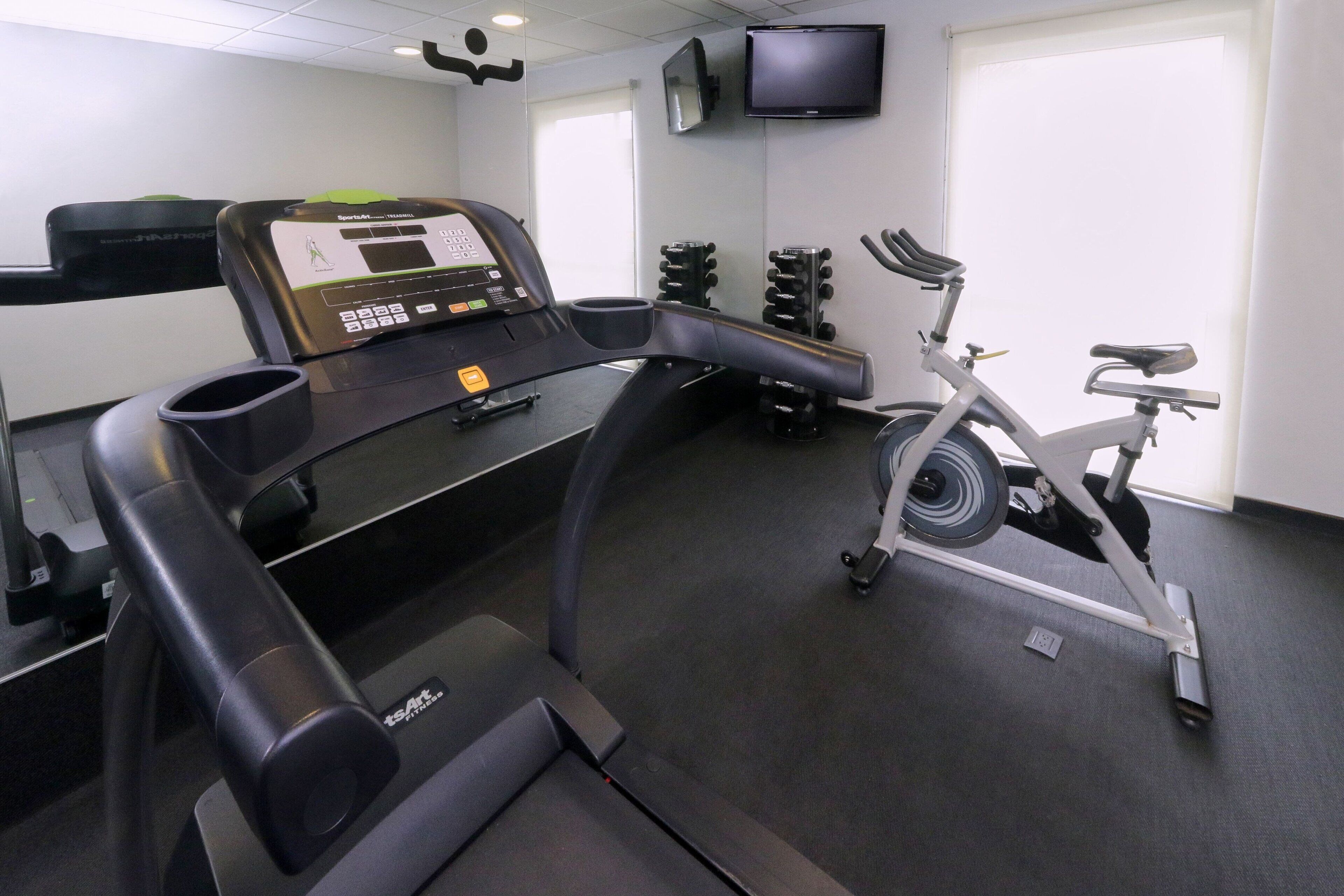 A gym with a treadmill, stationary bike, and weight machines.