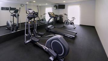 Un gimnasio con diversos equipos de ejercicio, incluyendo cintas de correr y elípticas.