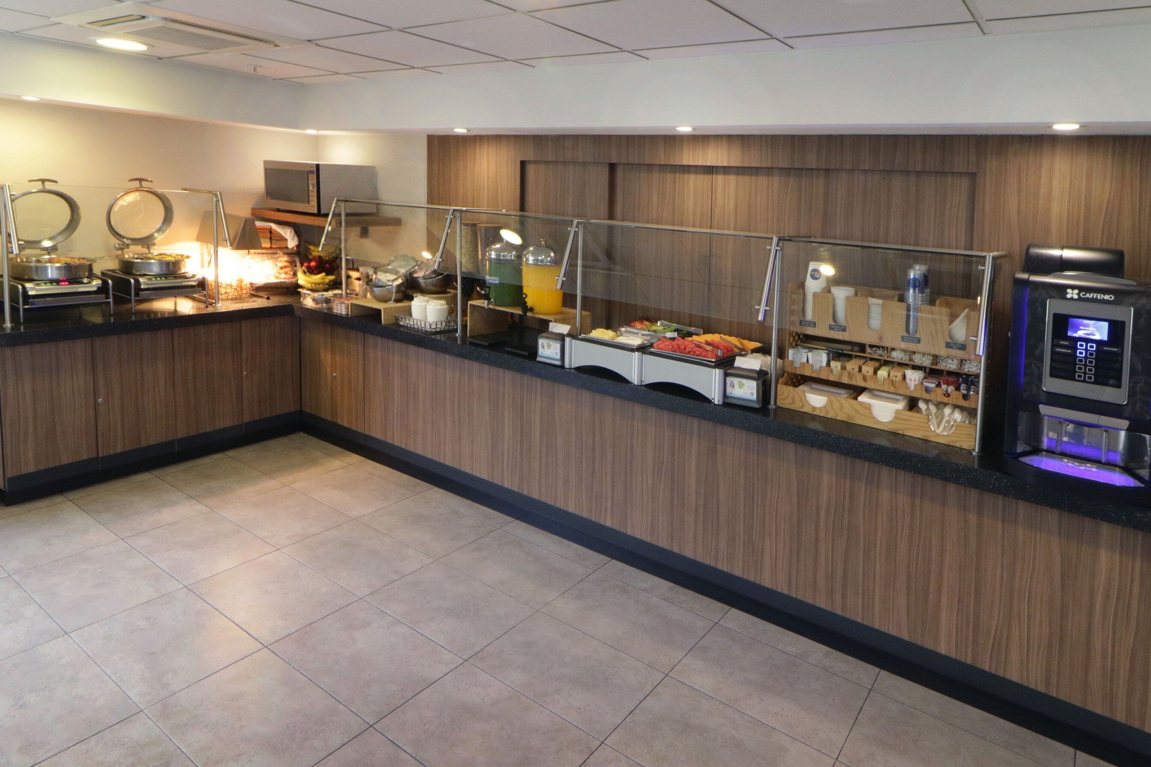 Un área de bufé con diferentes opciones de comida, un microondas y un dispensador de bebidas.