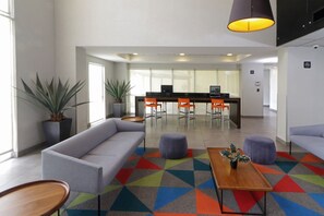 A modern lobby with a grey sofa, a wooden coffee table, and a colorful geometric carpet. - City Express by Marriott Tijuana Insurgentes (Tijuana)