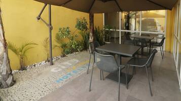 Un espace extérieur aménagé en terrasse, avec une table et des chaises, entouré de murs jaunes et de plantes en pot.