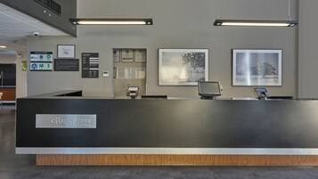 Un mostrador de recepción con una paleta de colores negro y gris, detalles de madera en la base, y certificados y documentos enmarcados en la pared.