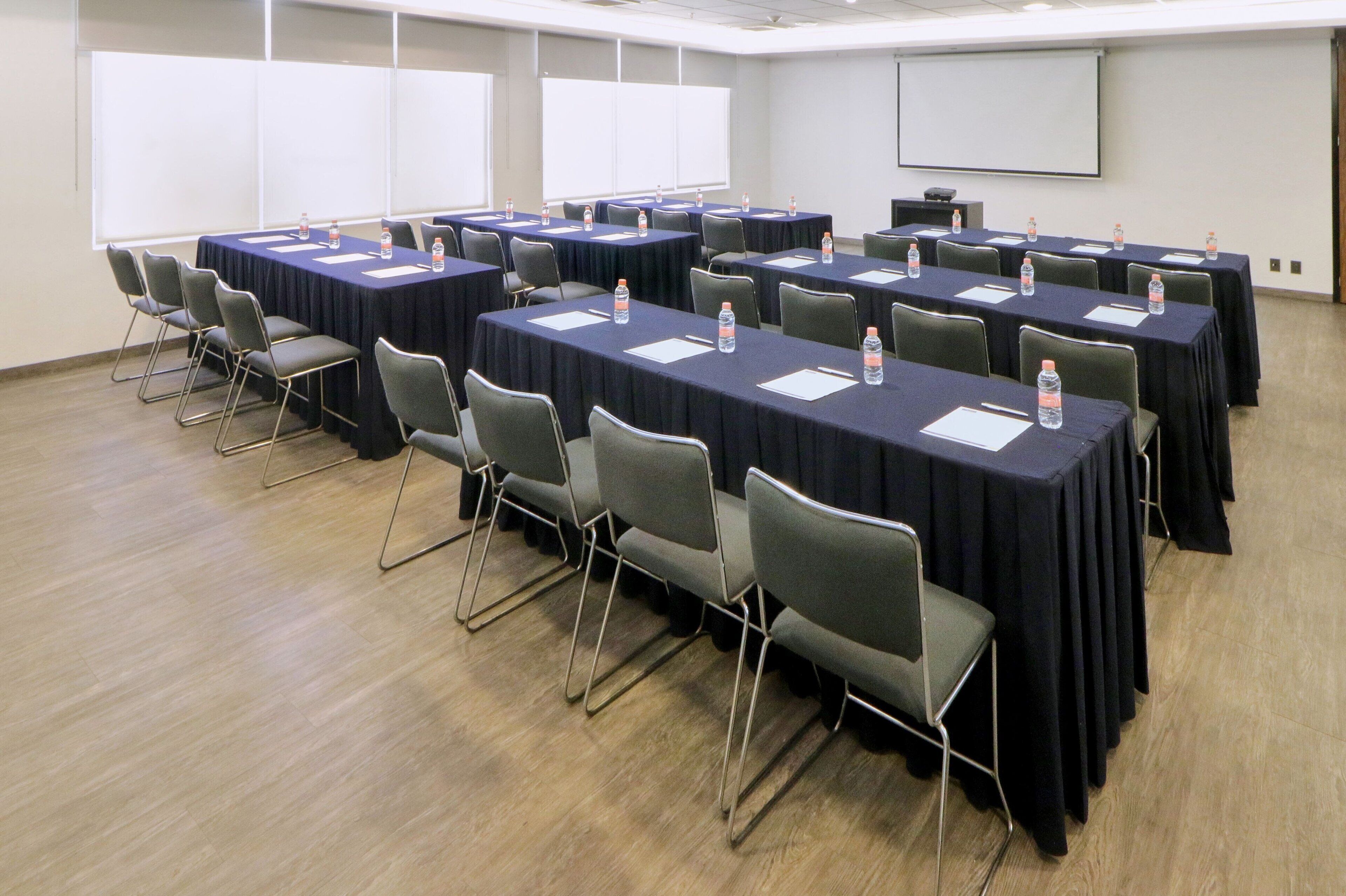 A conference room with multiple tables and chairs, equipped with water bottles and nameplates.