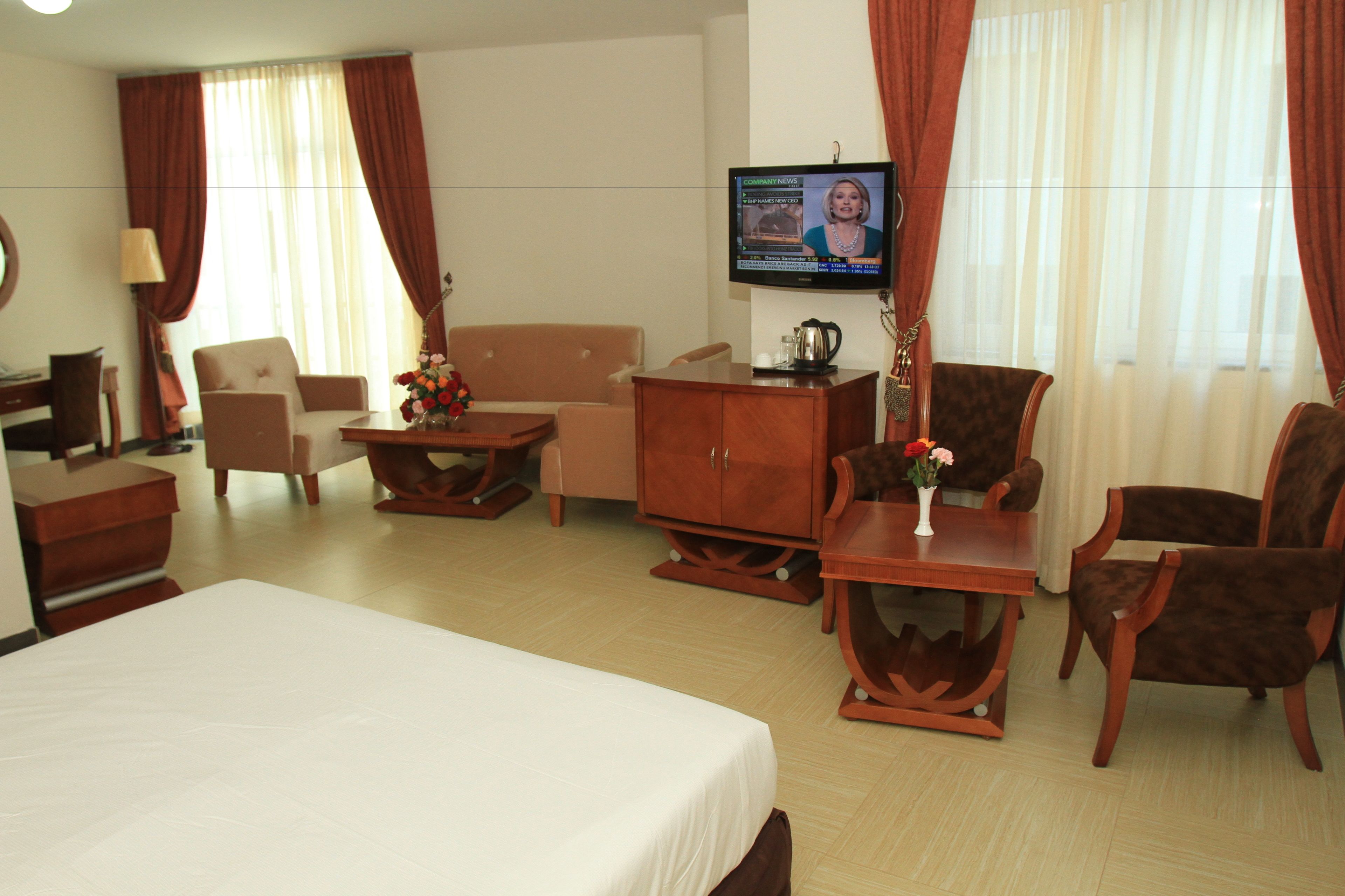 A hotel room with a bed, a desk, a chair, a sofa, a TV, and a coffee table.