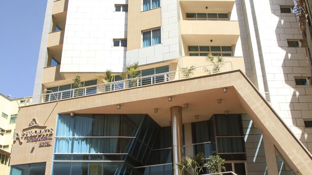 A multi-story building with a modern design, featuring a prominent entrance with a staircase, large windows, and potted plants. - Aphrodite International Hotel (Addis Ababa)