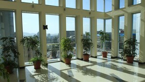 A spacious lobby with large windows, potted plants, and a tiled floor. - Aphrodite International Hotel (Addis Ababa)
