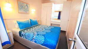 A bedroom with a bed, nightstand, and a wall-mounted light fixture. - Golden Glow Motel (Rotorua)