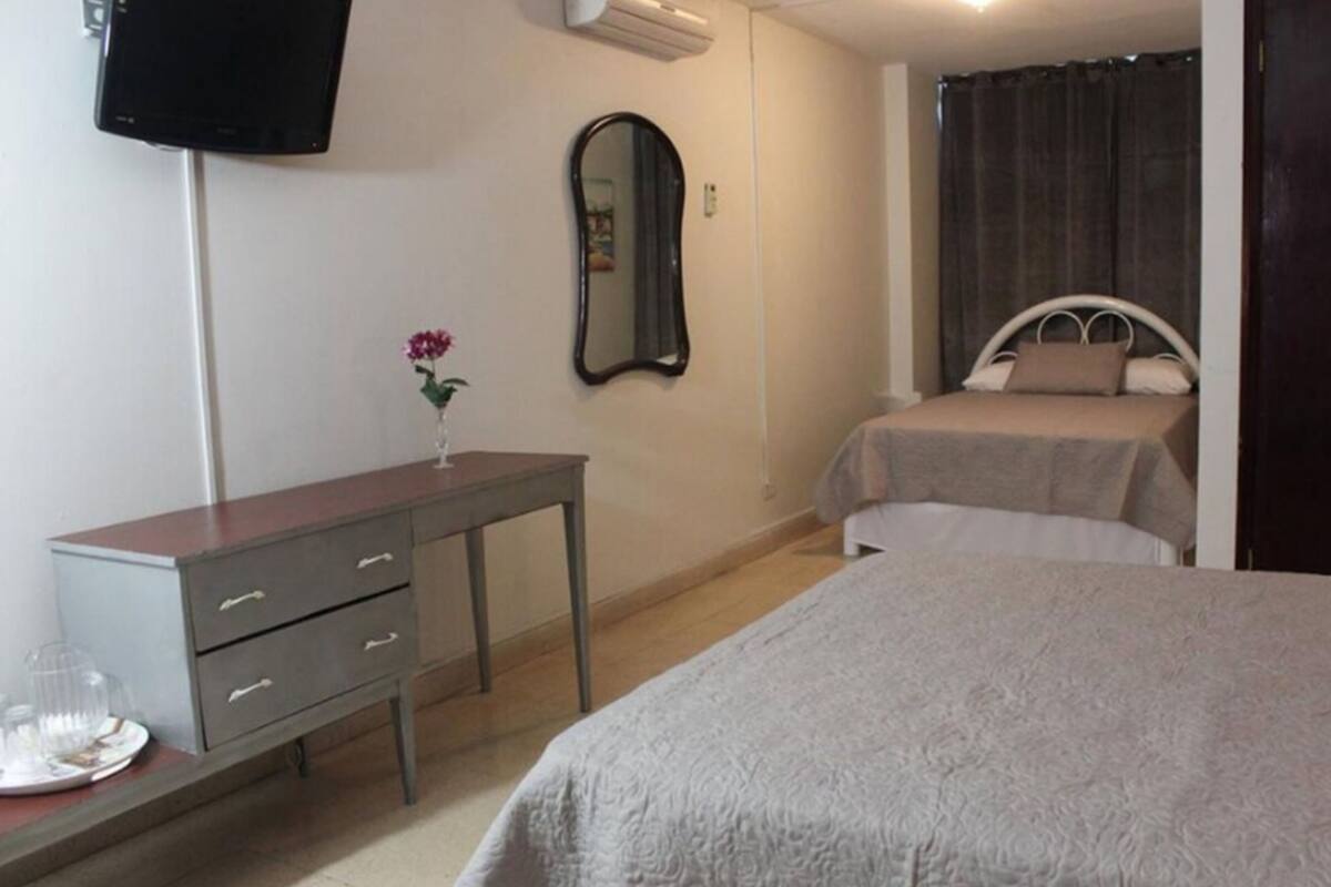 Un dormitorio con dos camas, un tocador, un espejo y un televisor.