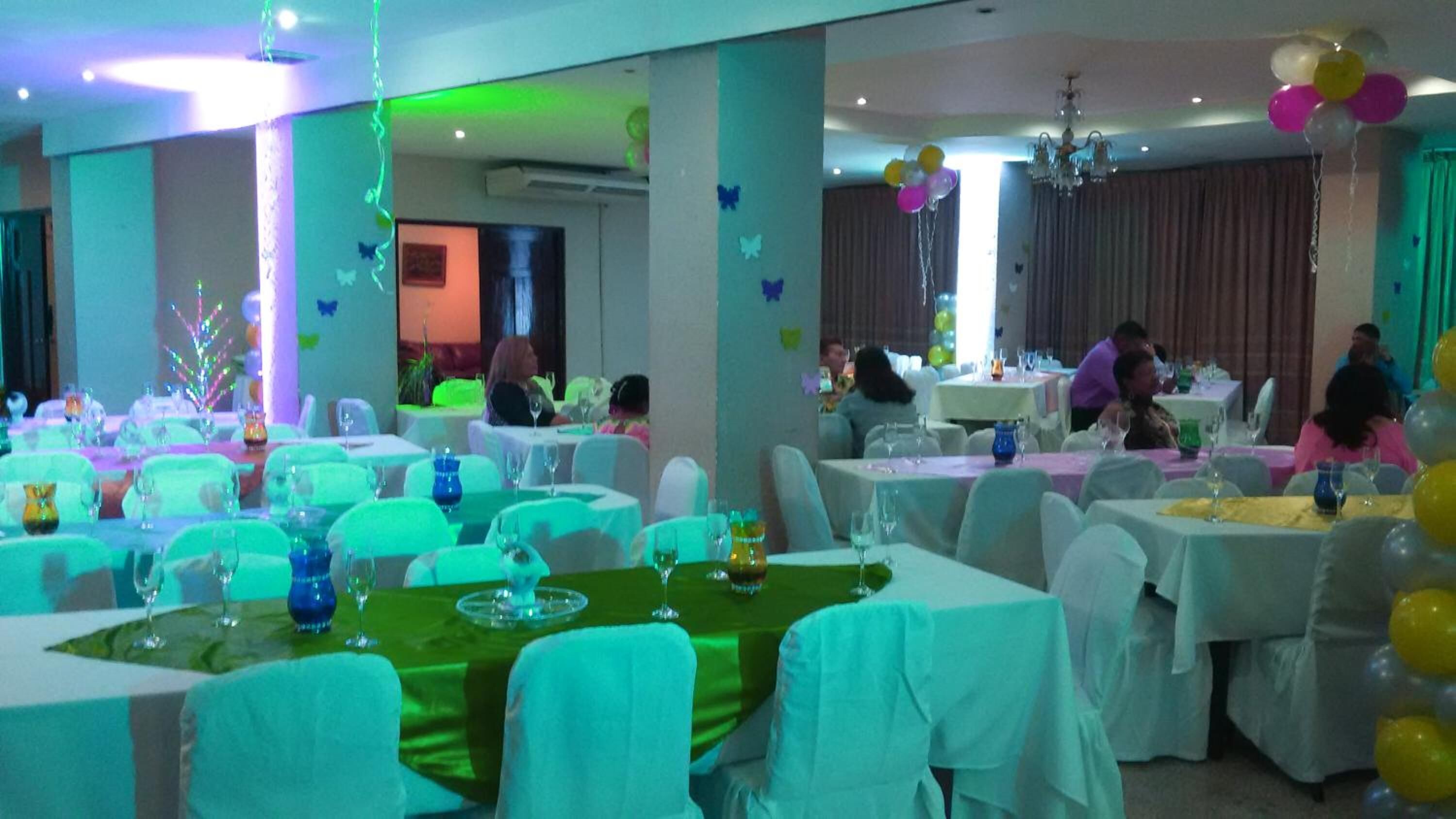 Un salón de banquetes con mesas redondas, manteles blancos y sillas.