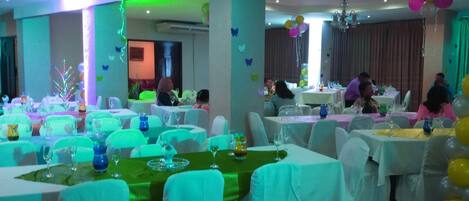 Un salón de banquetes con mesas redondas, manteles blancos y sillas.
