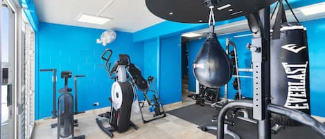 Ein Fitnessraum mit Trainingsgeräten, einem Boxsack und blauen Wänden.