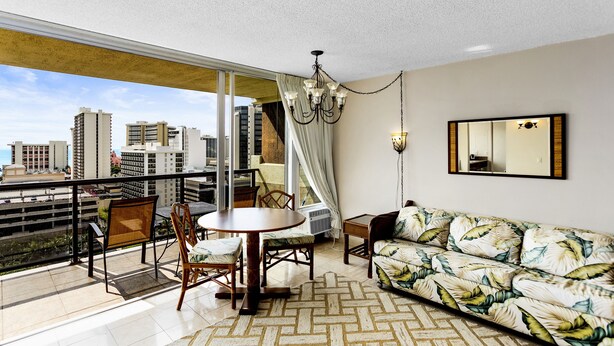 A balcony with a dining table, chairs, and a sofa. - Waikiki Beach Condominiums (Honolulu)